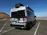Silver Thor Sequence rv rental, with bike rack, parked at a desert mountain viewpoint under clear blue skies.