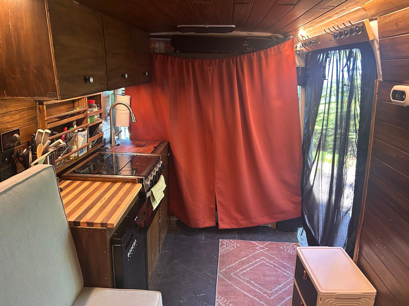 Cozy rv rental van interior showcasing a compact kitchenette with sink, stove, wood counters, and comfortable seating. — photo 20
