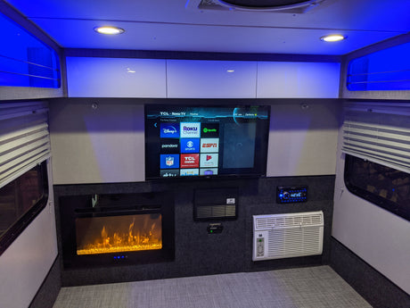 RV rental interior: TV with Roku, electric fireplace, AC, and blue ambient lighting creating a comfortable living space.