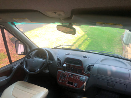 Inside an RV rental van: Driver's view showing the dashboard, steering wheel, and the road ahead through the windshield.