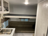 RV rental interior featuring bunk beds, a dinette lounge, and kitchenette area. Ideal for travel.