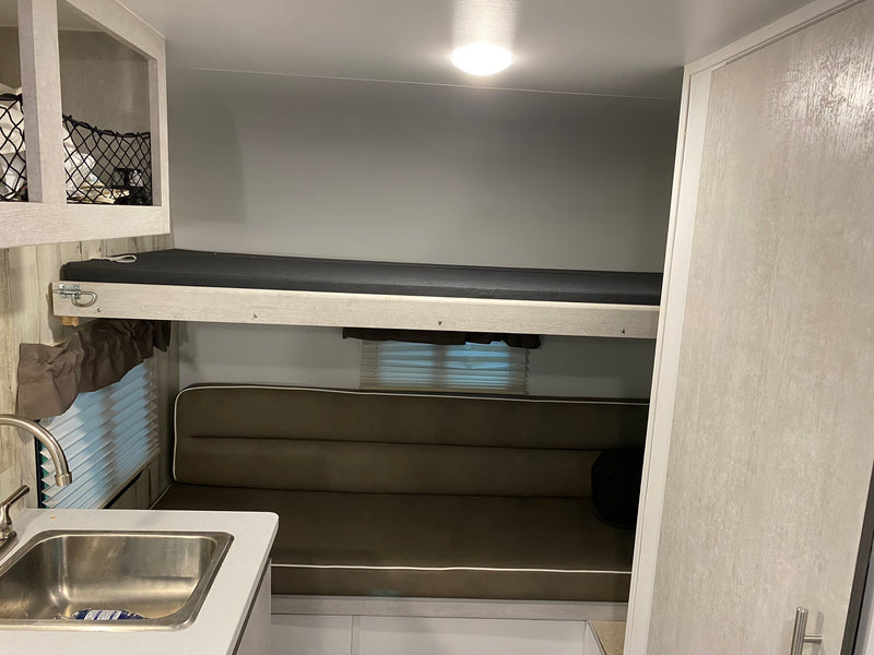RV rental interior featuring bunk beds, a dinette lounge, and kitchenette area. Ideal for travel. — photo 7