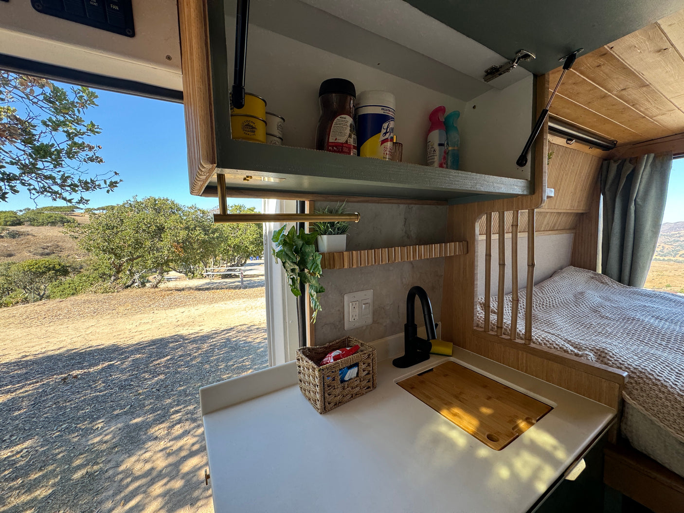 RV rental interior features a functional kitchen, bed, and stunning natural outdoor views.
