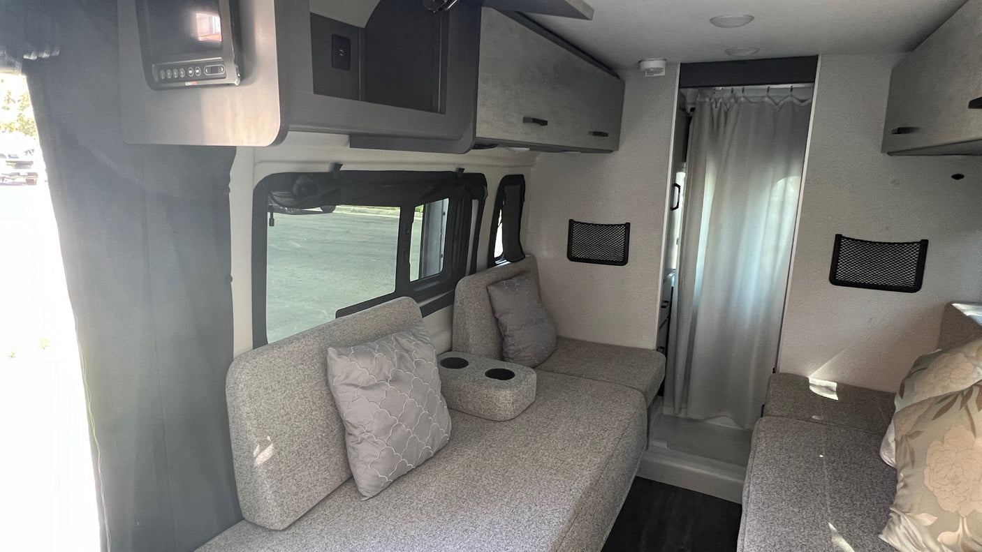 RV rental interior: A compact and functional living space with upholstered seating, storage, and shower access.