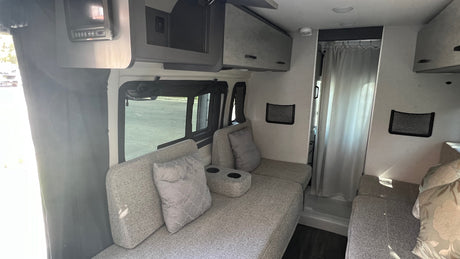 RV rental interior: A compact and functional living space with upholstered seating, storage, and shower access.