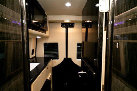 Luxury rv rental van interior featuring a modern kitchen with a microwave and sink, perfect for comfortable travel.