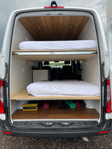 Inside an RV rental: custom camper van with dual bunk beds, wood ceiling, and floor for mobile living.