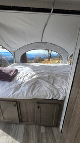 Enjoy breathtaking mountain views from a comfortable pop-up camper RV rental bed. Ideal for scenic travel!