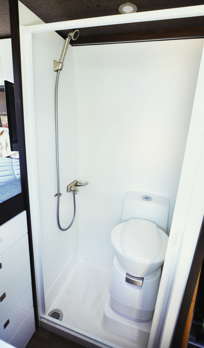 Explore this RV rental's compact wet bath, featuring a handheld shower and modern toilet. — photo 10