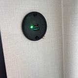 RV rental essential: A USB-A and USB-C charging port with a green light on a textured interior wall, ready for devices.