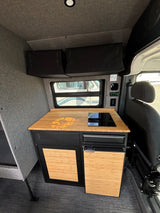 RV rental: Modern camper van interior featuring a bamboo kitchen counter with induction cooktop and compact fridge.