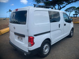 White camper van RV rental with roof rack, parked on a dirt lot next to a Hawaiian beach with palm trees.