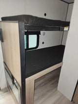 This RV rental features cozy bunk beds with mattresses, a small window, and wood-look flooring, ideal for a travel trailer.