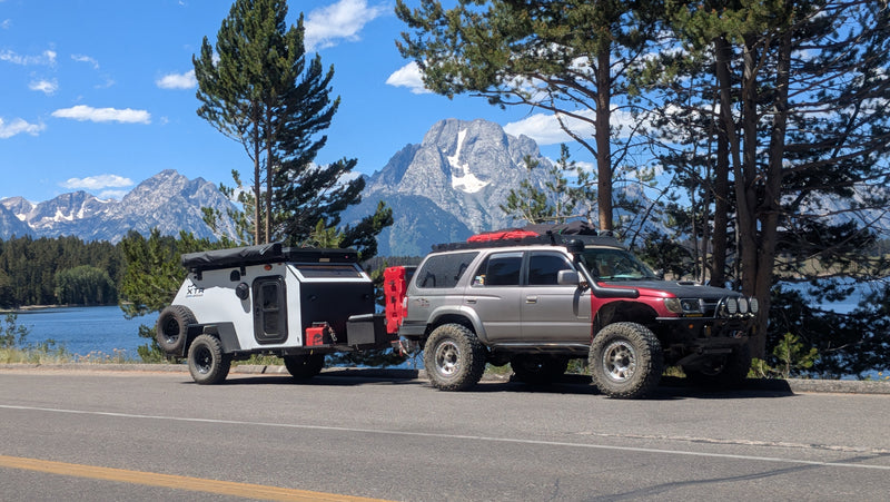 Modified SUV towing an XTR off-road camper by a lake & snow-capped mountains. Consider this RV rental for adventure! — photo 16