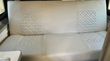 Clean RV rental dinette with light, patterned bench seat upholstery. Ideal for travel comfort.