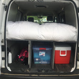 RV rental: Van interior showing organized bed platform, under-bed storage with cooler, and gear.