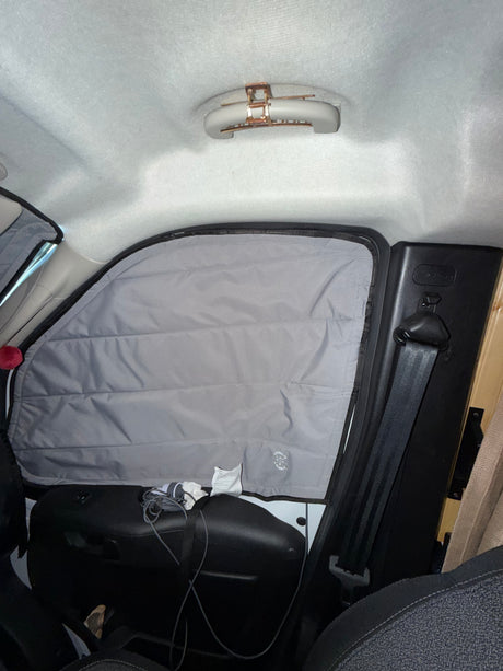 RV rental camper van interior. Features a "LIVING IN A BUBBLE" window shade, seatbelt, and ceiling clip for van life comfort.