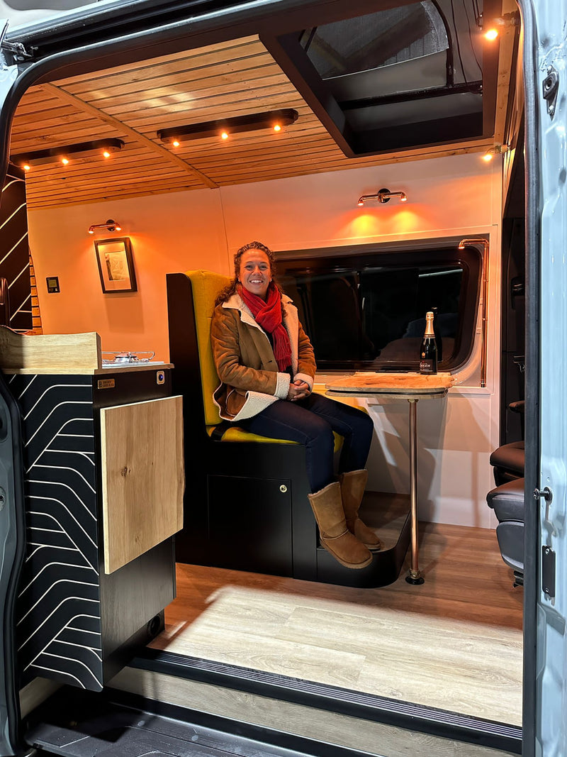 Woman enjoys a modern campervan interior from open door, featuring warm lighting & wood details. Ideal RV rental. — photo 17