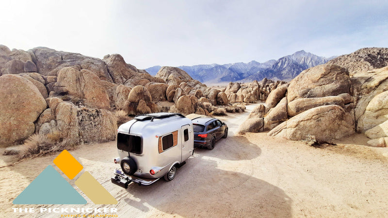 RV rental for desert adventures: A silver trailer towed by an SUV on a road, surrounded by rocks and mountains. — photo 8