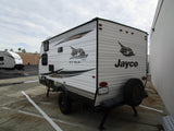 This Jayco Jay Flight SLX BAJA travel trailer, a potential RV rental, is shown parked from its side and rear view.