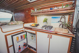 Inside a custom camper van: cozy bed, full kitchen with fridge, and stunning beach view, ideal for an RV rental getaway.