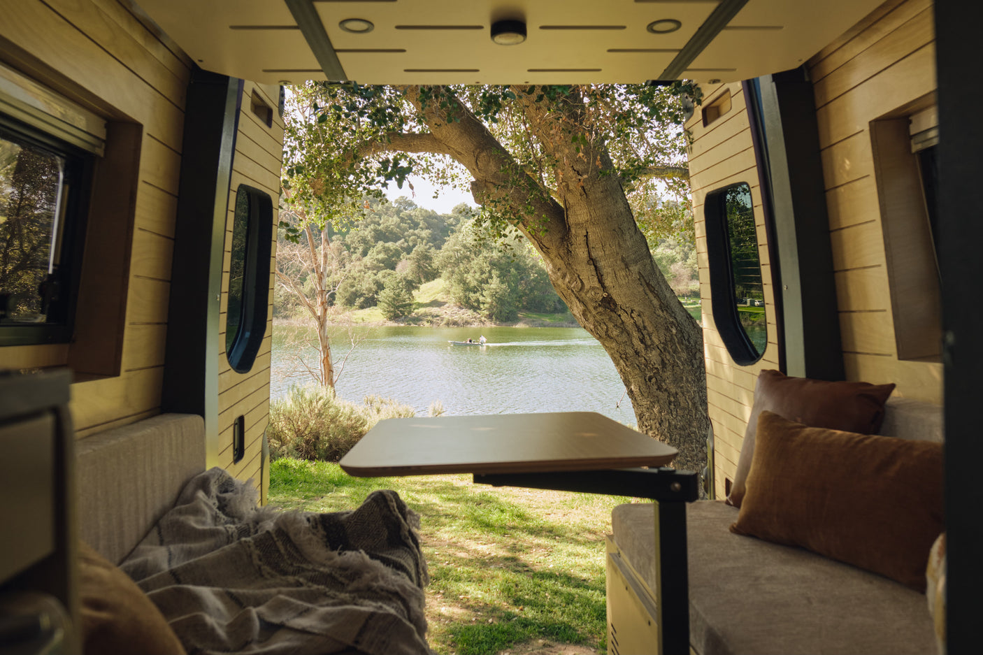 Experience nature's beauty from your cozy rv rental! Wood-paneled interior, lake view with boat, and lush greenery.