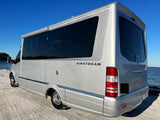 Experience the open road with this stunning silver Airstream rv rental, parked on a sandy shore by blue water.
