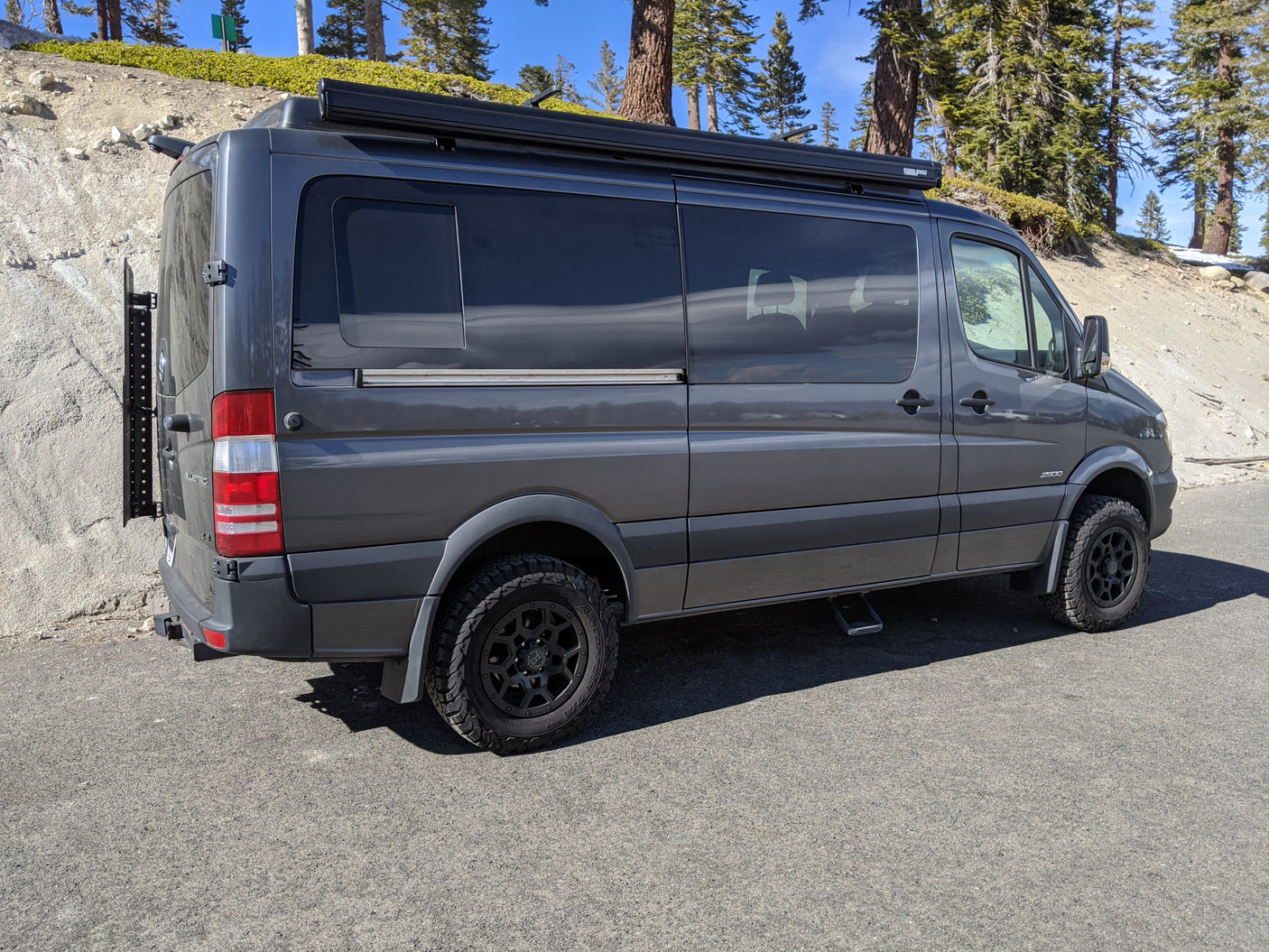Gray Mercedes Sprinter camper van, an RV rental, ready for exploration with off-road tires and rooftop awning.