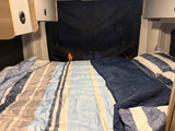 Cozy RV rental bedroom with striped bedding and sleeping bag, perfect for camping.
