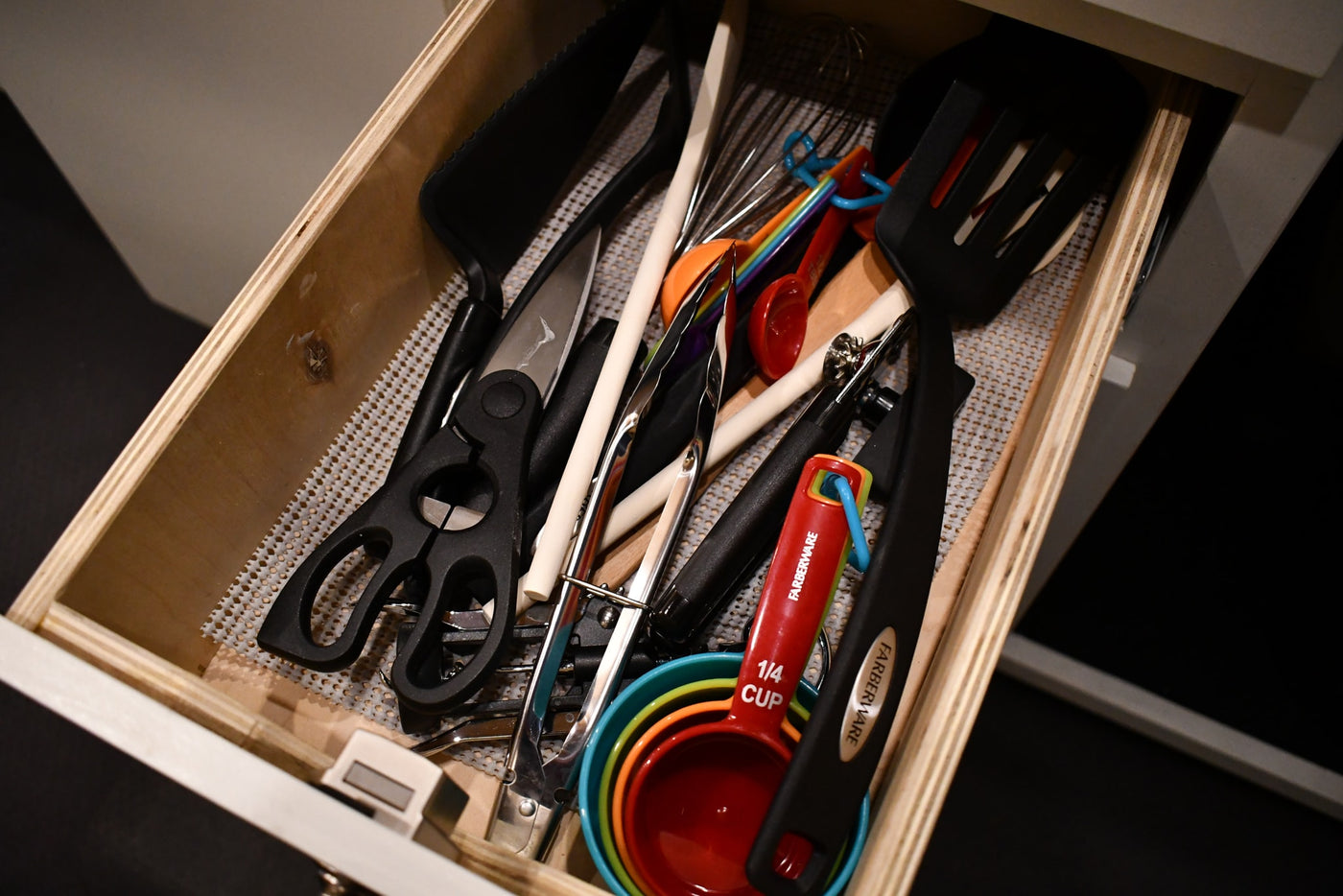 RV rental kitchen drawer stocked with cooking utensils, including measuring cups, spatulas, and kitchen scissors. — photo 10
