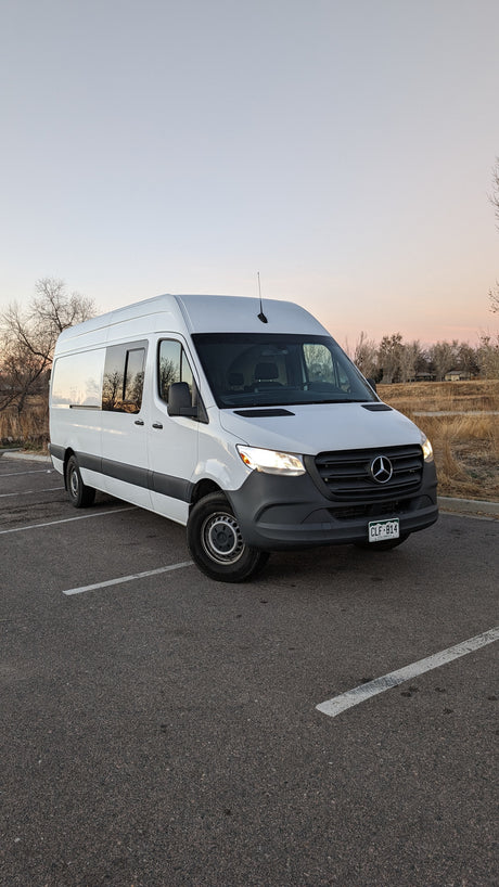 White Mercedes Sprinter camper van for rv rental, parked at dusk. Perfect for adventure.