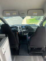 Interior view of an RV rental, showing the Ford dashboard, front seats, and part of the camper conversion.