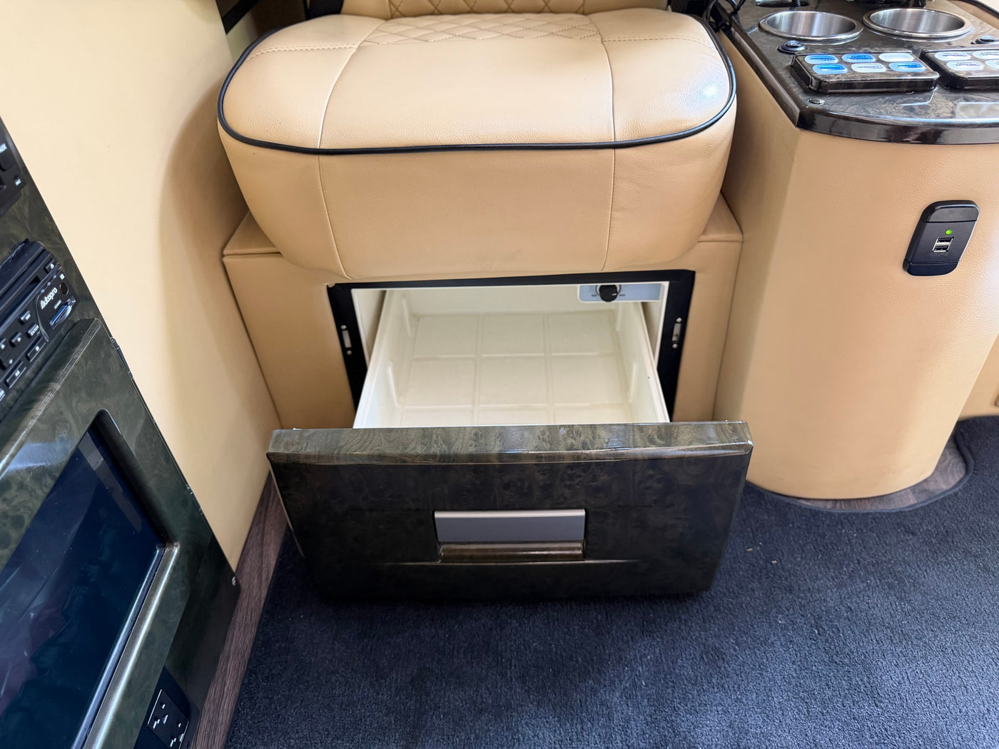 Plush beige seat and open mini-fridge in a luxury RV rental. Features include USB charging and an entertainment console for comfort. — photo 17