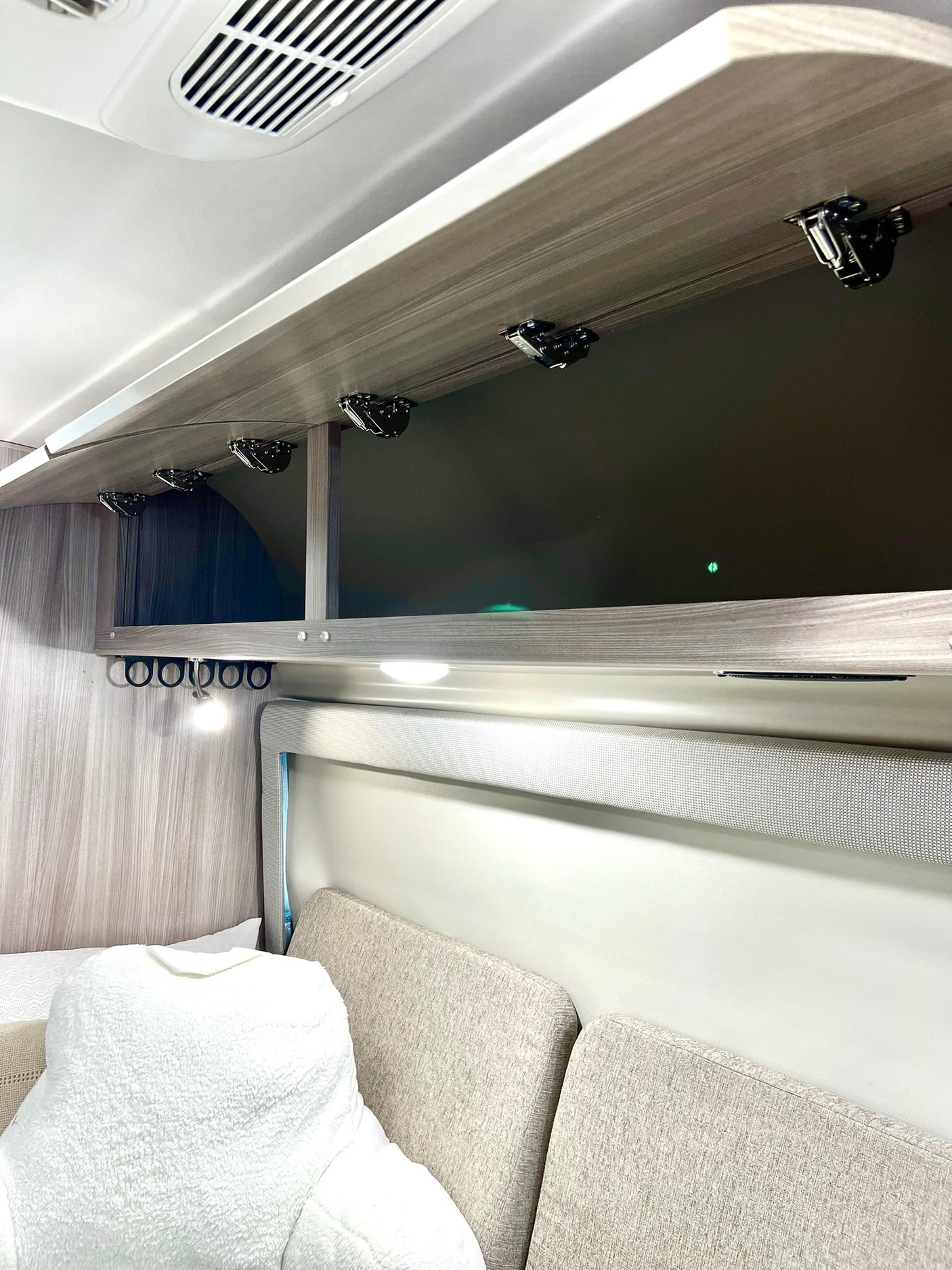 RV rental: Bright interior featuring open overhead cabinets, a ceiling vent, useful hooks, and plush seating for comfortable travel.
