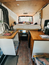 Cozy RV rental interior: fully equipped camper van with bed, kitchen, & smart storage for comfortable travel.