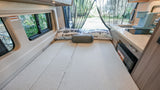 Cozy RV rental interior with a comfy bed, compact kitchen, and views of nature through the mesh screen at the back.