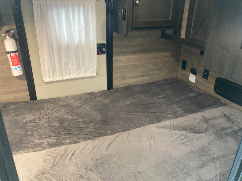 RV rental interior: two grey-blanketed bunks, a fire extinguisher, white curtain, and wood-paneled walls. Cozy sleeping space. — photo 7
