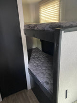 Explore this RV rental's comfy bunk beds! A practical interior sleeping area with grey mattresses & window blinds.