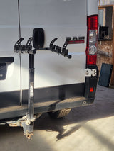 Rear view of a white Ram ProMaster **rv rental**, equipped with a Thule bike rack on its hitch. Ideal for outdoor adventures.