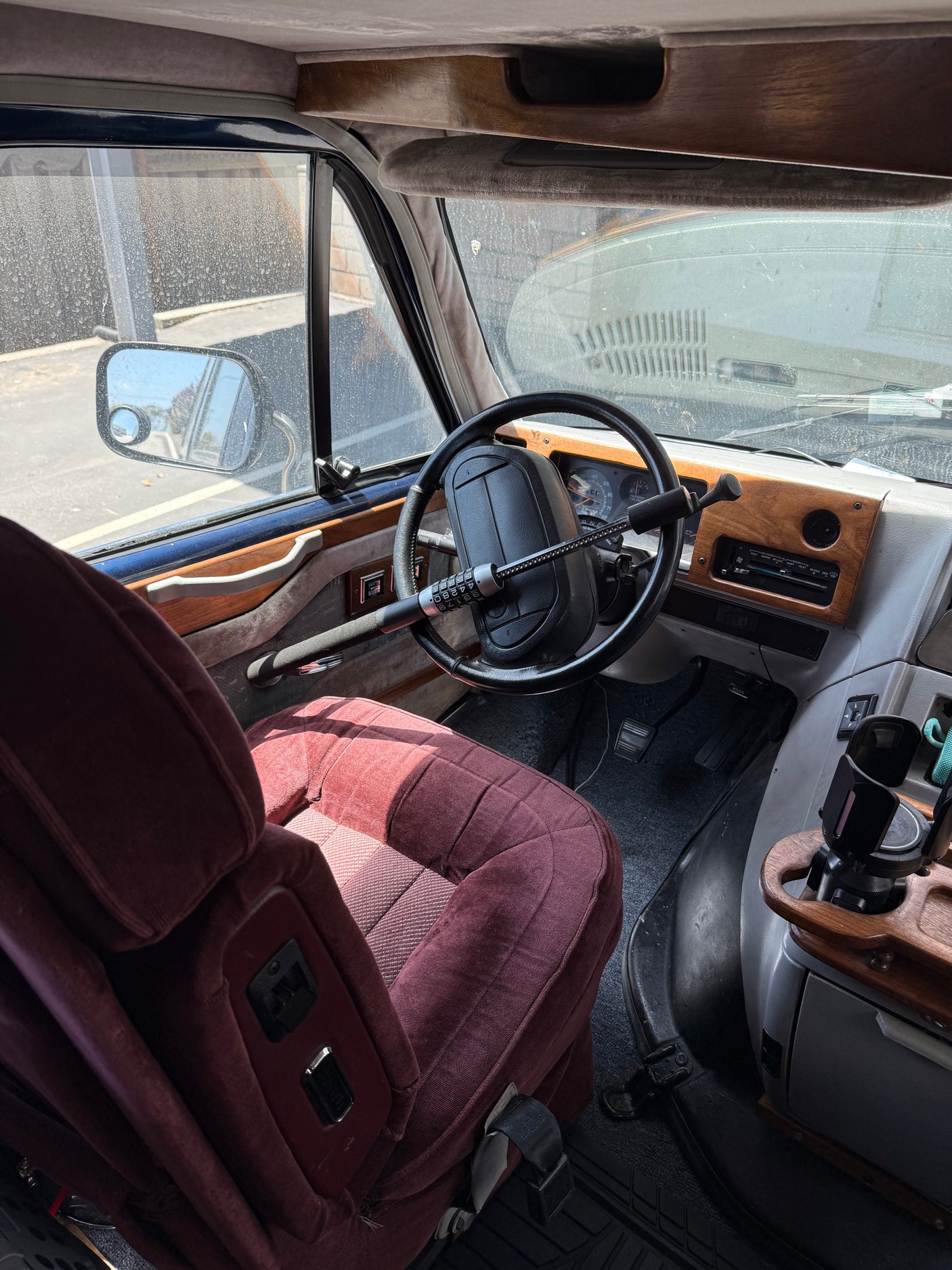 Inside this RV rental: driver's seat, steering wheel with security lock, dashboard, and custom wood trim.