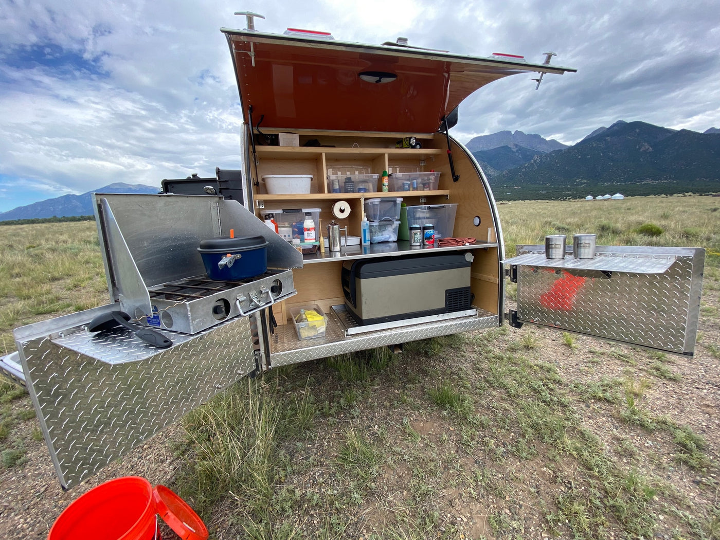 Fully equipped teardrop RV rental kitchen setup outdoors with mountains & yurts. Perfect for camping! — photo 3