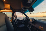 Inside a cozy rv rental, witness a beautiful ocean sunset from the driver's seat. Perfect for travel and relaxation.