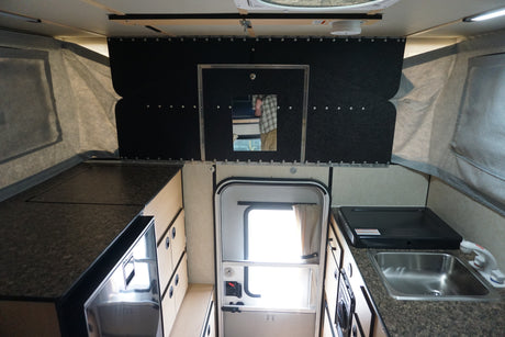 Explore this RV rental's interior: a compact pop-up camper kitchen with sink, stovetop, fridge, and storage.