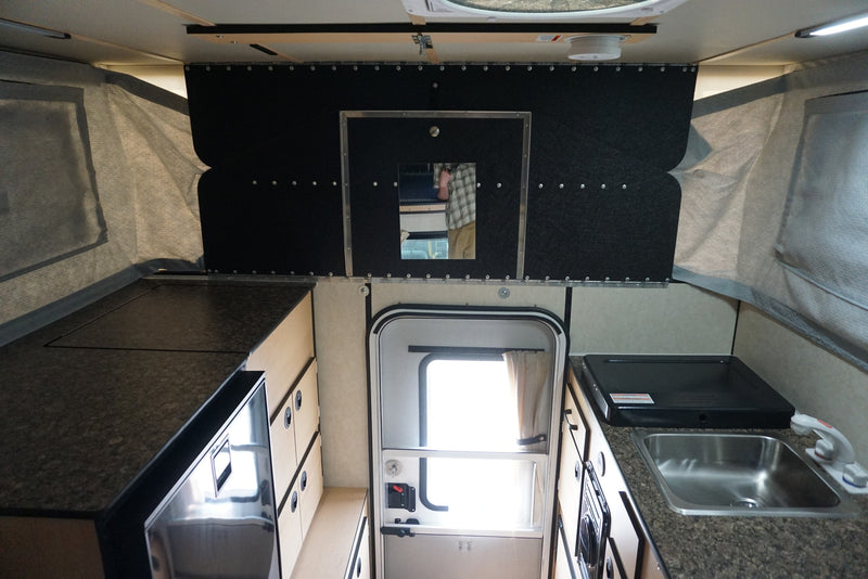 Explore this RV rental's interior: a compact pop-up camper kitchen with sink, stovetop, fridge, and storage. — photo 7
