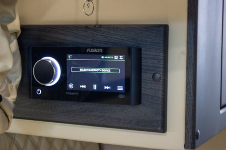 A Fusion MS-RA770 stereo in an RV rental, displaying "SELECT BLUETOOTH DEVICE" with a bright control knob.