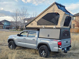 Silver Toyota Tacoma with a Lone Peak pop-up rooftop tent & truck camper. An ideal RV rental for off-grid camping adventures.