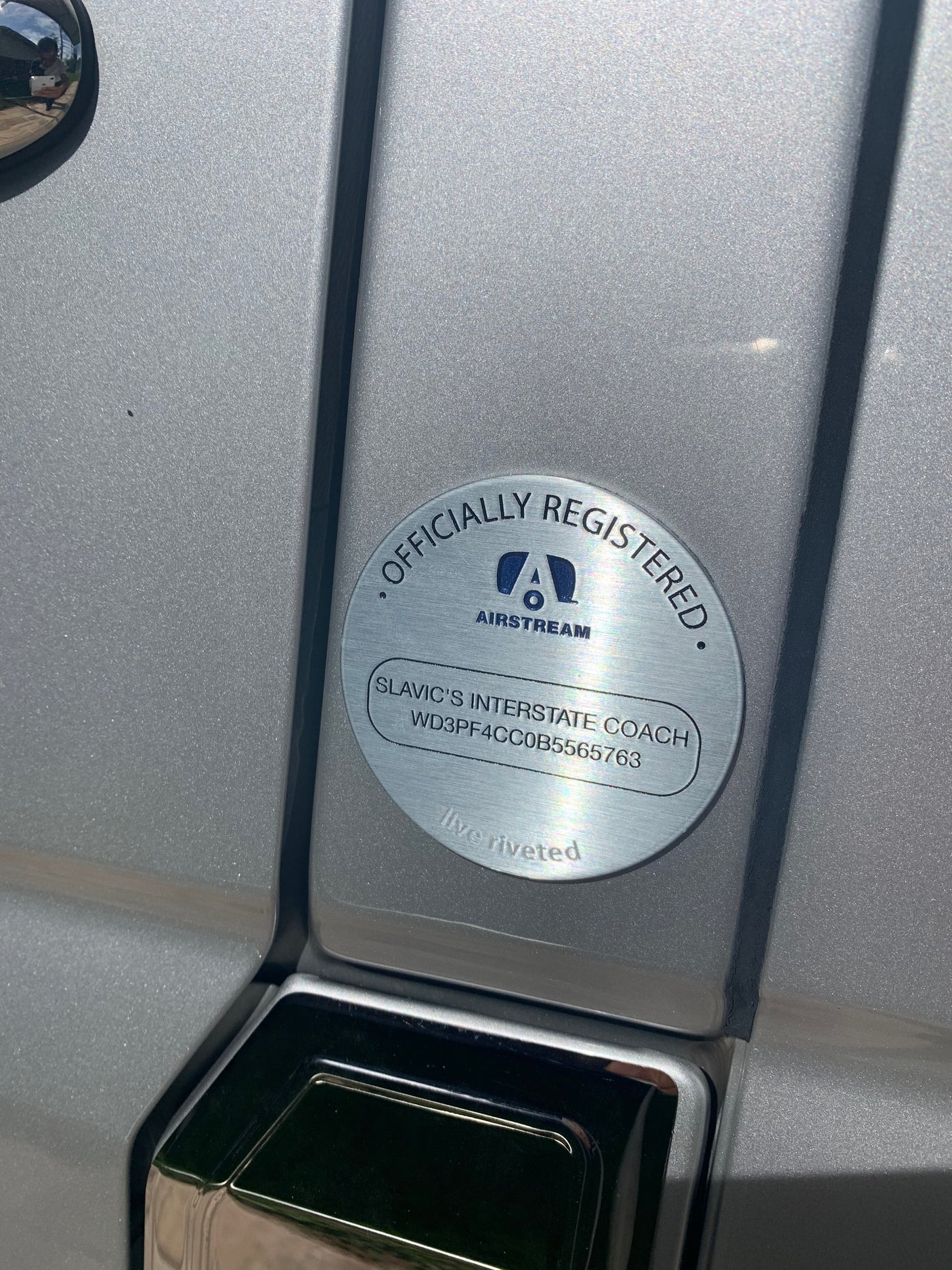 Officially registered Airstream RV rental plaque. "Slavic's Interstate Coach" and VIN visible on the brushed metal surface.