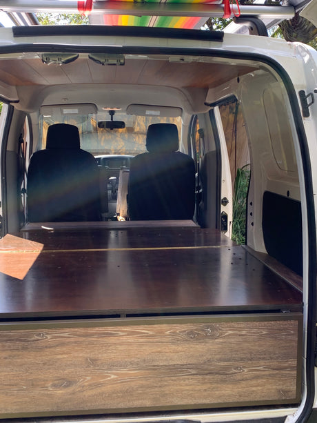 rv rental camper van interior: a wooden bed platform with storage and front seats visible, ready for adventure.