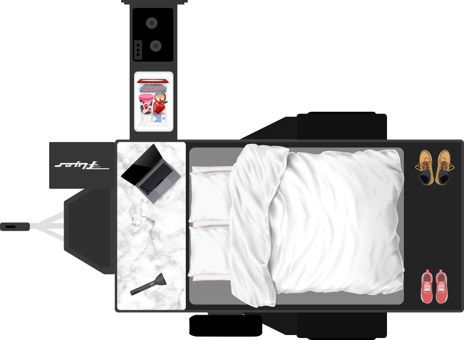 Overhead view of an RV rental interior: bed, counter with laptop, mini-fridge with snacks, and shoes. Compact mobile living.