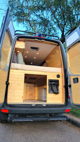 Spacious custom camper van interior, featuring a cozy bed, ample storage, and an outdoor shower. Perfect for an RV rental adventure!